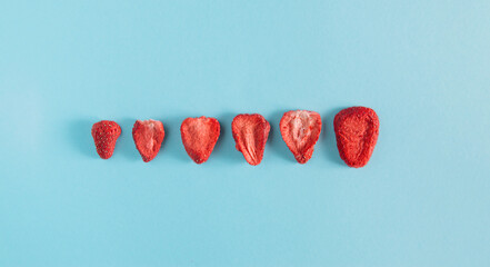 Dehydrated sliced strawberries on the pastel sky-blue background. Dried fruit slices. Freeze...
