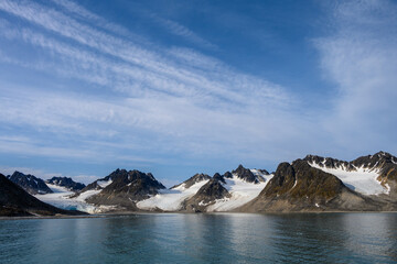 Dramatic clouds in the sky above the mountain peaks in Magdalena Fjord, Svalbard, in the summer arctic
