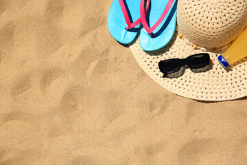 Straw hat, sunglasses, flip flops and refreshing drink on sand, flat lay with space for text. Beach accessories - obrazy, fototapety, plakaty