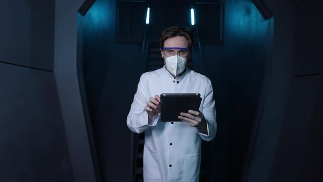 Male medical worker holding his tablet and wearing protective mask and glasses. Portrait of a man working in biochemical laboratory. High quality 4k footage