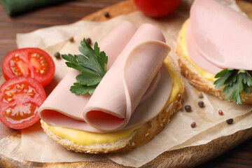 Delicious sandwiches with boiled sausage, cheese and tomato on table, closeup