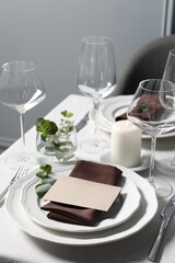 Beautiful table setting with blank card and floral decor indoors