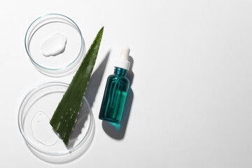 Bottle of cosmetic serum, aloe vera leaf and petri dishes with samples on white background, flat...