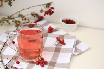 Cup with hawthorn tea and berries on table. Space for text