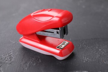 One red stapler on black textured table