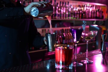 Bartender making fresh alcoholic cocktail at counter in bar, selective focus