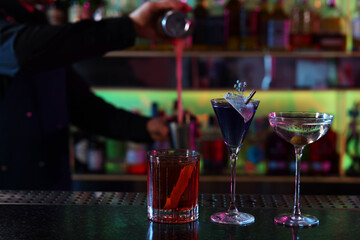 Bartender making fresh alcoholic cocktail at counter in bar, selective focus