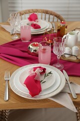 Color accent table setting. Plates with pink napkins, glasses and cutlery, closeup