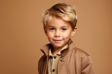 Cute little boy with blond hair and brown coat on brown background