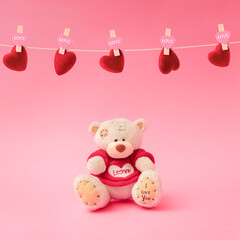 Love composition made of teddy bear and holding a heart-shaped on pastel pink background. Minimal concept of Valentine's Day or love. Creative art, minimal aesthetics.