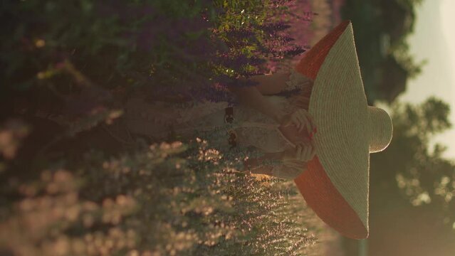 Portrait of young blond woman in a wide-brim straw hat in the beautiful colorful violet floral field