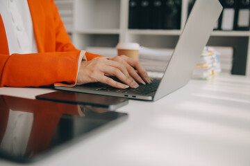 Close up Business woman using calculator and laptop for do math finance on wooden desk, tax, accounting, statistics and analytical research concept