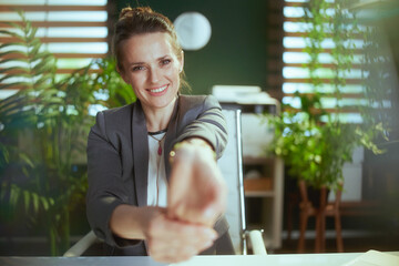smiling business owner woman in green office stretching hands