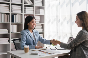 Two businesswoman shaking hands after discussion about new business project and deal together