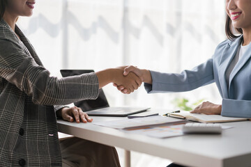 Two businesswoman shaking hands after discussion about new business project and deal together