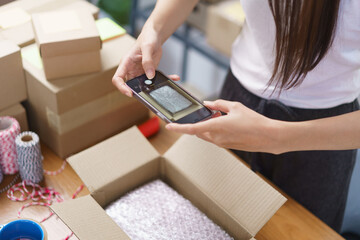 Online selling concept, Asian business women take a picture while packing product into parcel box