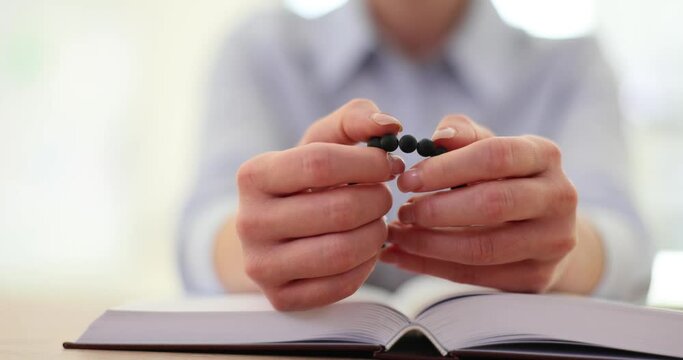Bible and black rosary hands of woman in prayer studying religion at table with Christian faith and knowledge of God