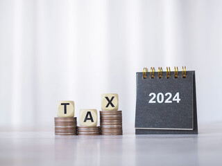 2024 desk calendar and Wooden block with word TAX on stack of coins. The concept of saving money for payment tax, Financial, Investment and Business growing in year 2024.