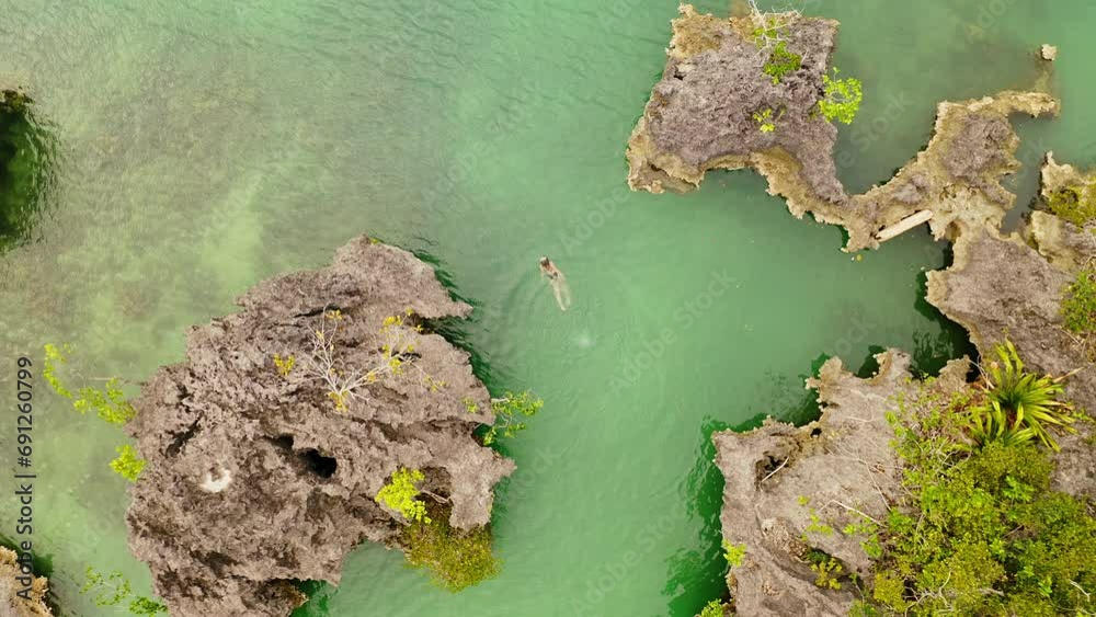 Wall mural Drone of ocean, above and woman swimming in beach for holiday, summer vacation and adventure in tourism. Aerial view of a person snorkeling in water, sea or coral reef in Raja Ampat Island, Indonesia