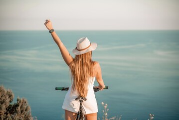 Naklejka premium A woman cyclist on a mountain bike looking at the landscape sea. Adventure travel on bike.