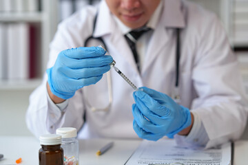 Young doctor holds a syringe and a vial with a vaccine for the treatment of disease. Injections in...