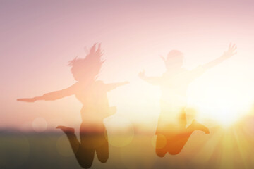 two women friend jumping at sunrise blur background
