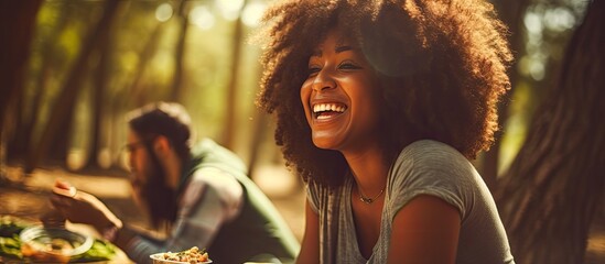Happy African American woman eating outdoors with friends in a forest.
