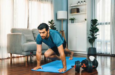 Athletic and sporty man doing mountain climber on fitness mat during home body workout exercise...