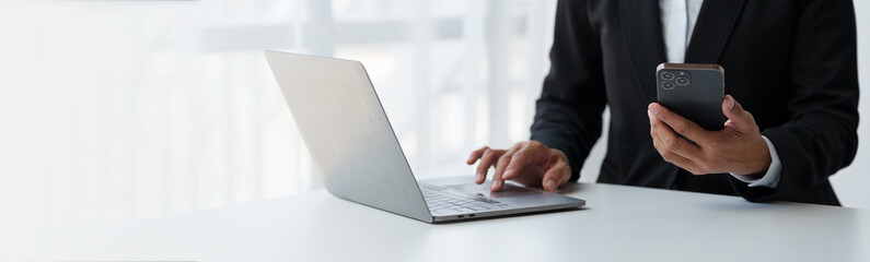 Businessman, investor analyzing stock market investment with financial panel, business intelligence on smartphone and laptop computer. Concept, technology, communication, copy space, banner, panorama