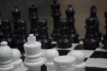 Large chess set with large white chess pieces in foreground, large black chess pieces in background