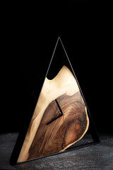 Wooden triangular wall clock on dark grey background. Luxurious accessories for home, office or...