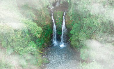 Aerial view of waterfall, natural forest and mysterious trees and mountains. The waterfall has...