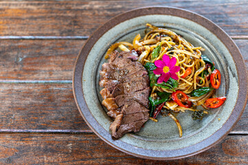 Stir-fried spaghetti with drunken beef on a wooden table