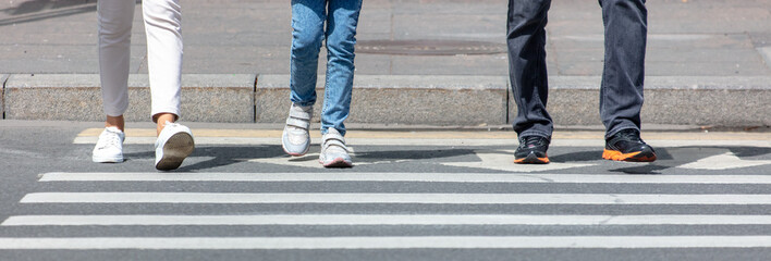 Three people are walking along a pedestrian crossing