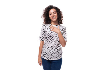 portrait of a young pretty well-groomed brunette curly woman dressed in a blouse with a pattern of peas on a white background