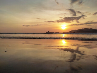 Fototapeta na wymiar The evening atmosphere at Pulau Merah Beach, Banyuwangi Regency, showing the sun setting in the Indian Ocean.