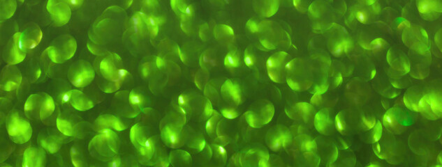 Blurred green sparkling background from sequins, macro. Shiny glittery bokeh of christmas garland.