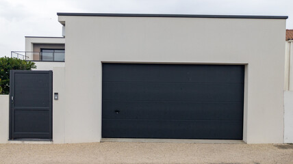 modern white facade house with gray garage door and grey portal pedestrian of suburb new house