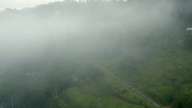Establishing Aerial Drone Shot through the Mist of Train Track in Hills around Ella Sri Lanka