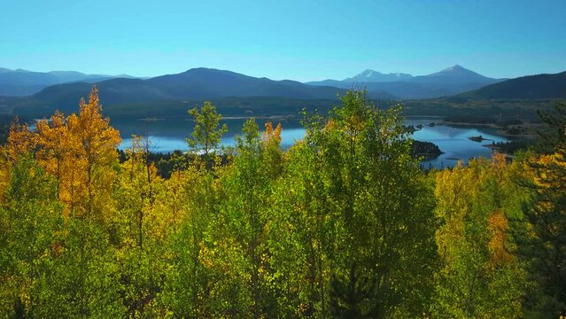 Early fall yellow colors Aspen trees Lake Dillon Colorado aerial cinematic drone morning view Frisco Breckenridge Silverthorne Ten Mile Range calm reflective water wide dolly jib upward movement