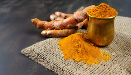 Ginger root and ginger powder in copper bowl on jute cloth