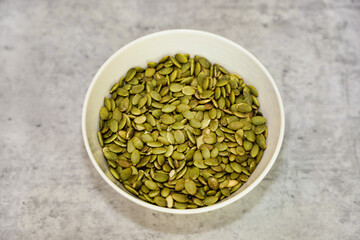 Roasted pumpkin seeds (pepitas) in a white bowl.
