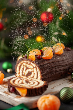 Yule log roll cake with chocolate ganache  on Christmas decorated background