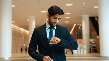 Caucasian smart business man looking at watch while waiting colleague. Executive manager wearing suit while standing at mall with blurred background. Investor wear blue suit check time. Exultant. - obrazy, fototapety, plakaty