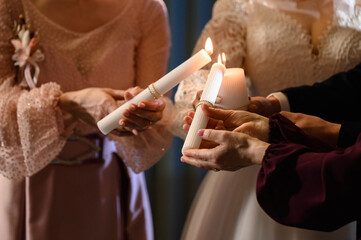 The bride and groom hold lit candles in their hands.