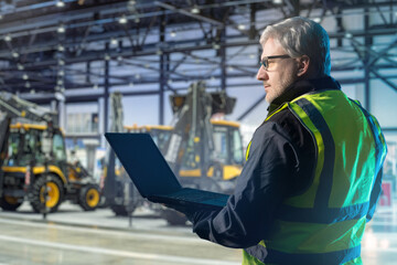 Man owner construction company. Worker in hangar with construction equipment. Businessman with...