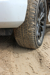 Sand on the tire tread of front wheel of the car on a sandy ground road 