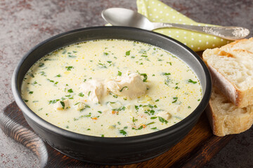 Romanian Sour Chicken Soup Ciorba Radauteana with vegetables and sour cream closeup on the plate on the table. Horizontal