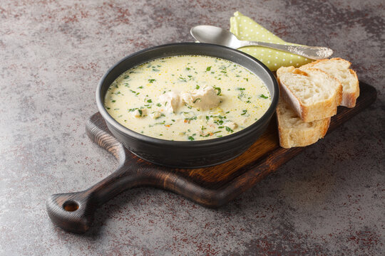 Ciorba Radauteana is a traditional Romanian soup made with a chicken, onions, sweet red pepper, celery, carrots, garlic, parsley, and sour cream closeup on the plate on the table. Horizontal