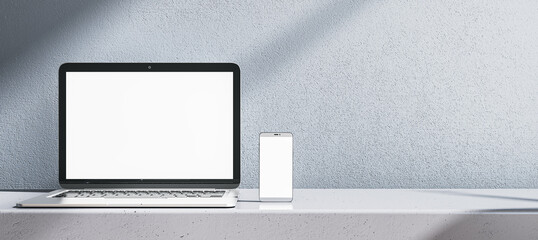 Close up of empty white laptop computer and smartphone on gray desk. Concrete wall background. Device presentation and online education concept. Mock up, 3D Rendering. - obrazy, fototapety, plakaty